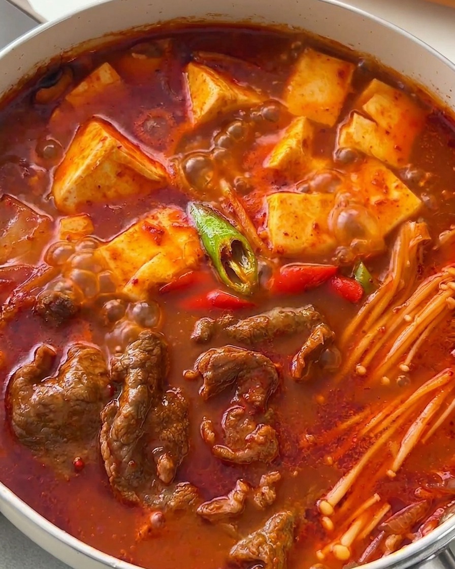 Gorąca patelnia z koreańską zupą kimchi udekorowaną plastrami zielonego i czerwonego chili.