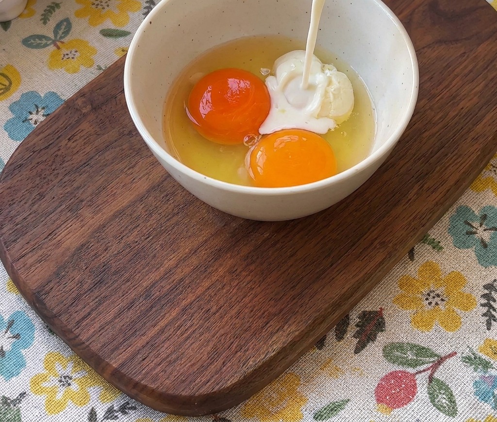 Mleko wlewane do miski z dwoma żółtkami.