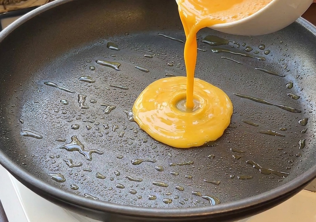 Masa jajeczna wlewana na rozgrzaną patelnię z olejem.