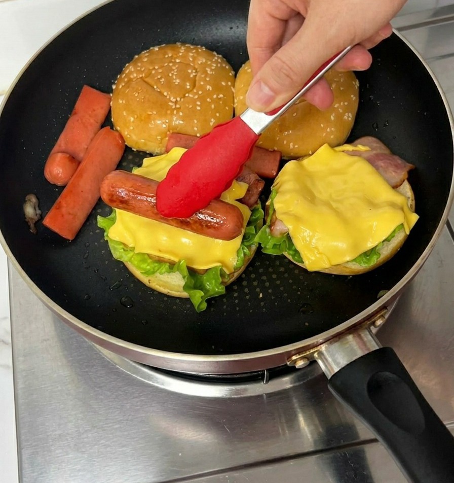 Szczypce kładące grillowaną parówkę na plaster sera w burgerze.