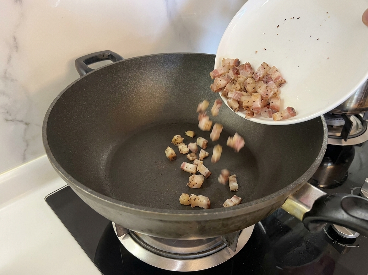 Surowe kawałki guanciale na zimnej, ciemnej patelni.