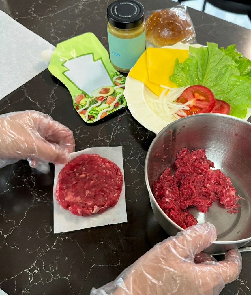 Surowy kotlet wołowy spłaszczony na kwadracie pergaminu obok miski z mięsem.