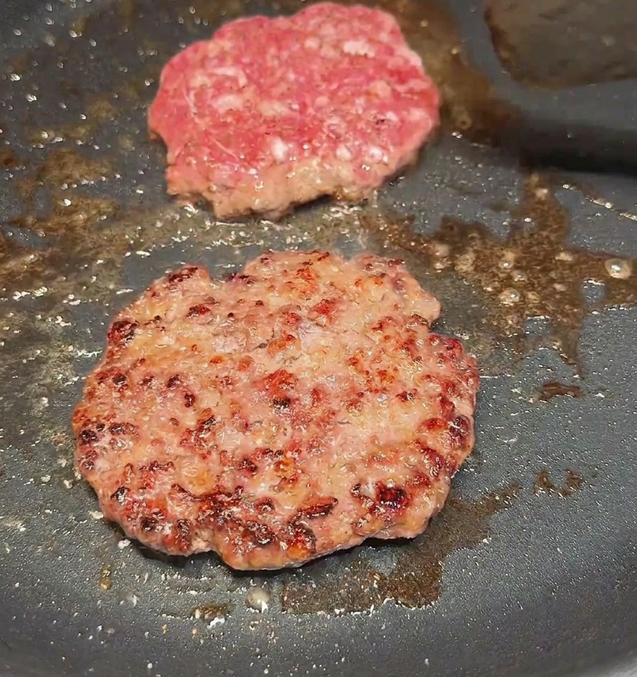 Łopatka obracająca kotlet wołowy na patelni, ukazująca mocno przyrumienioną skórkę.