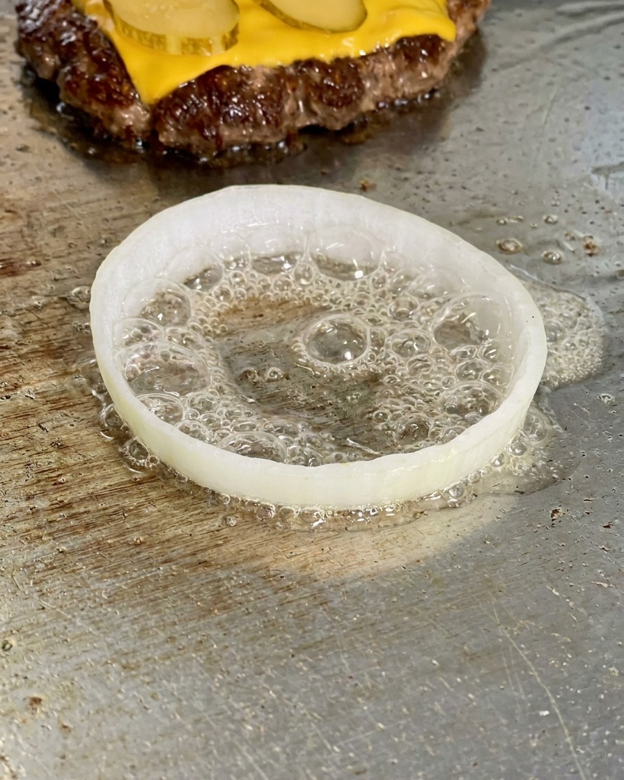 Plaster cebuli na grillu z wbitym do środka jajkiem.