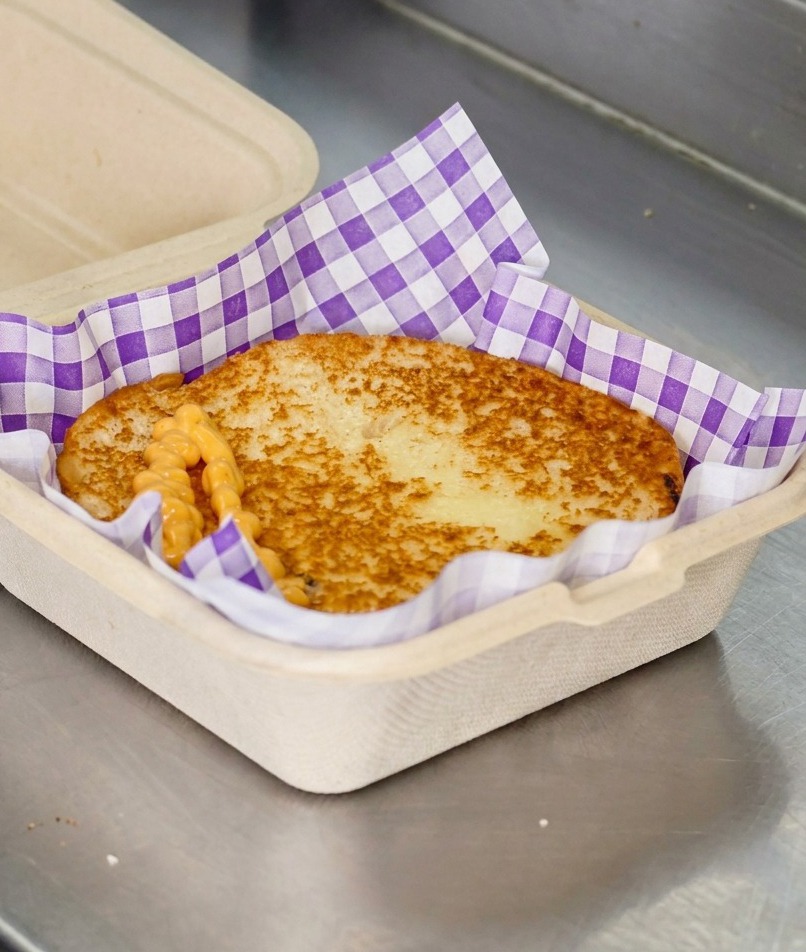 Pomarańczowy sos do burgerów nakładany zygzakiem na opieczoną bułkę.
