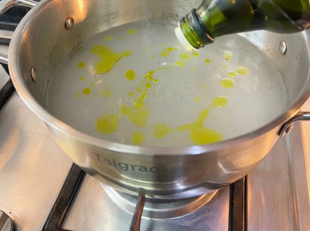 Surowy makaron spaghetti zanurzony w dużym garnku z wrzącą wodą.