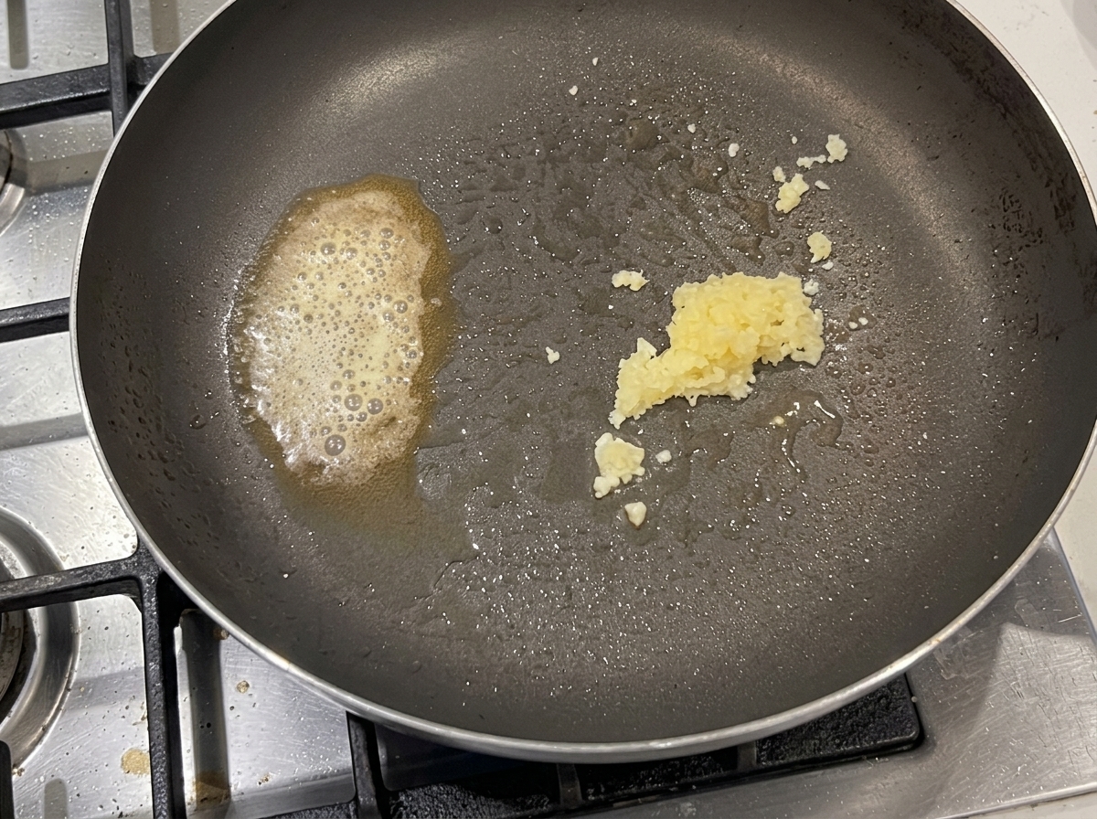 Ugotowany makaron mieszany z boczkiem, czosnkiem i chili na dużej patelni.
