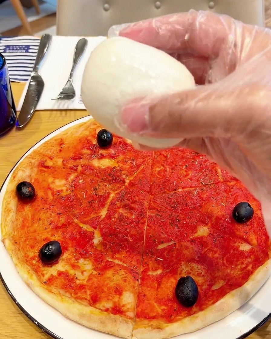 Kawałki świeżej mozzarelli di bufala układane na pizzy.