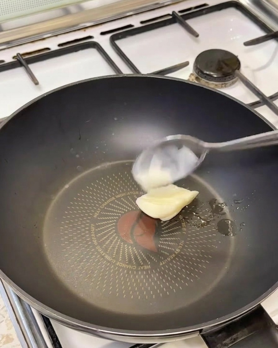 Łyżka białego smalcu rozpuszczająca się na gorącej patelni.