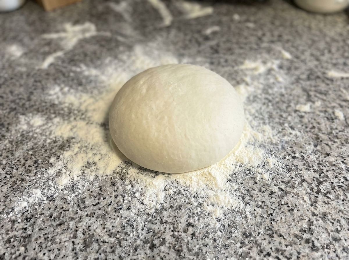 Ciasto układane i formowane w okrąg na powierzchni posypanej mąką.