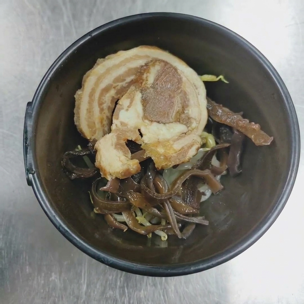 Zbliżenie na miskę z plastrem chashu i grzybami mun gotowymi do podania.