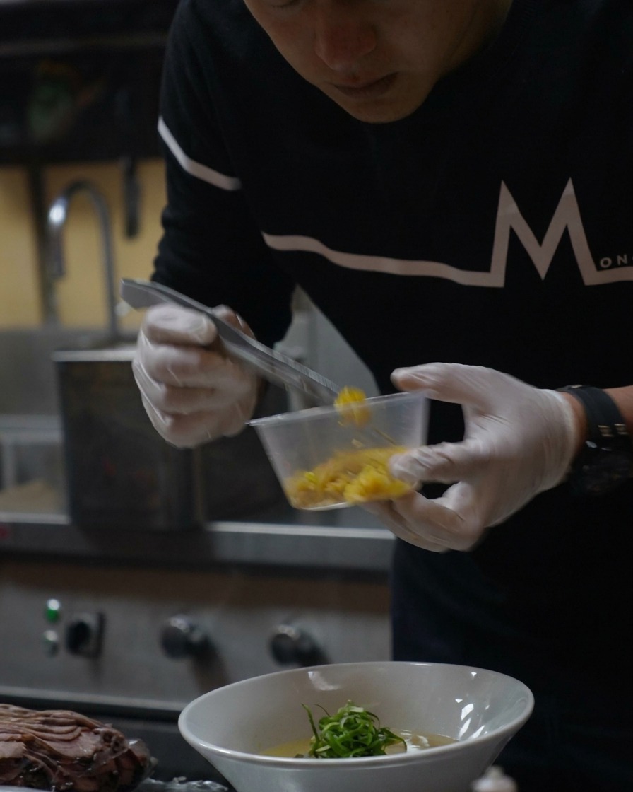 Mała łyżeczka jasnej, żółtej skórki z yuzu posypywana na gotowy ramen.