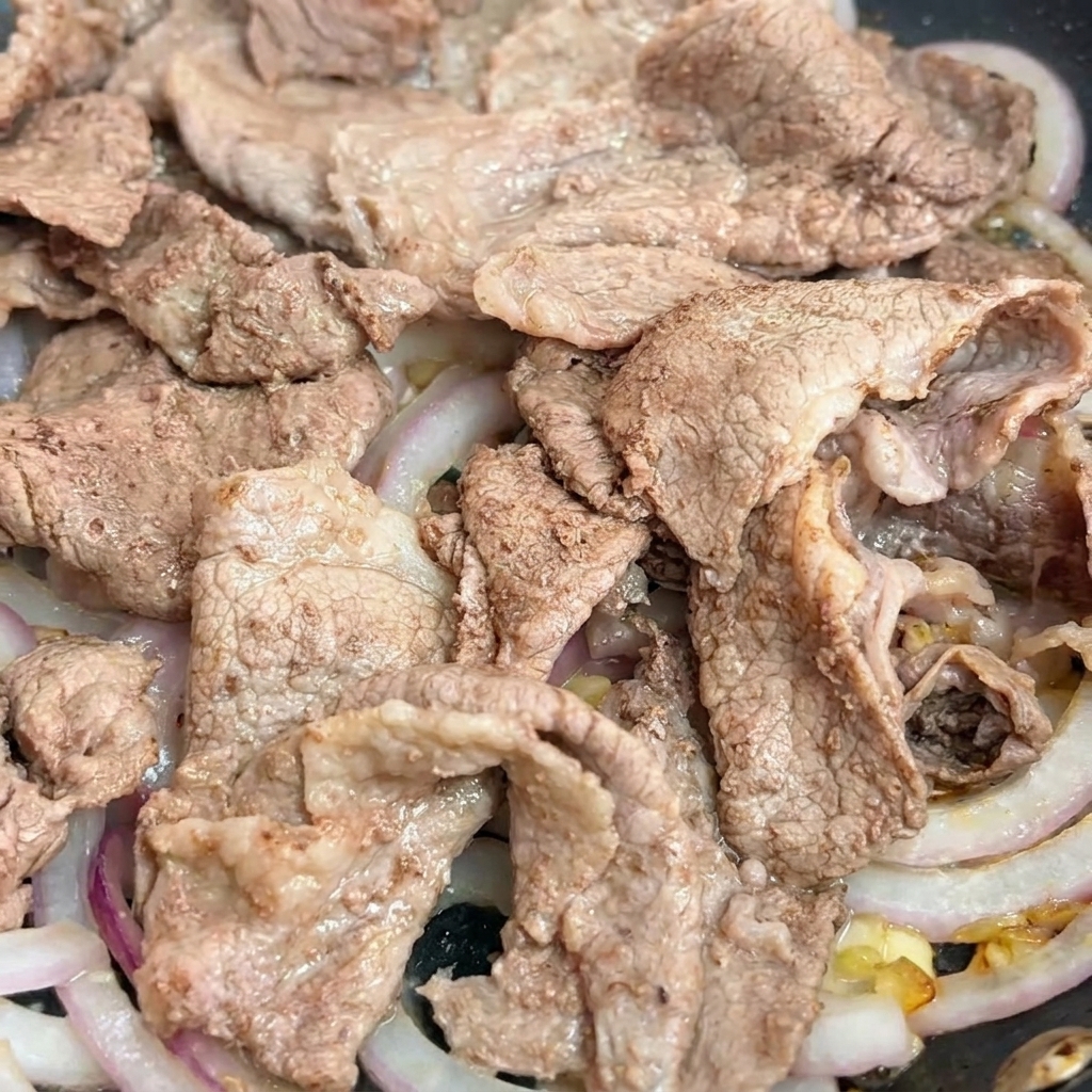 Ciemny sos teriyaki wlewany na wołowinę.