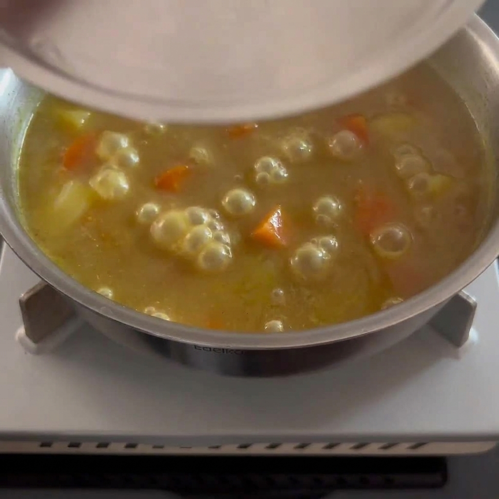 Gęsty, złocistobrązowy sos curry z widocznymi kawałkami miękkich ziemniaków i marchewki.