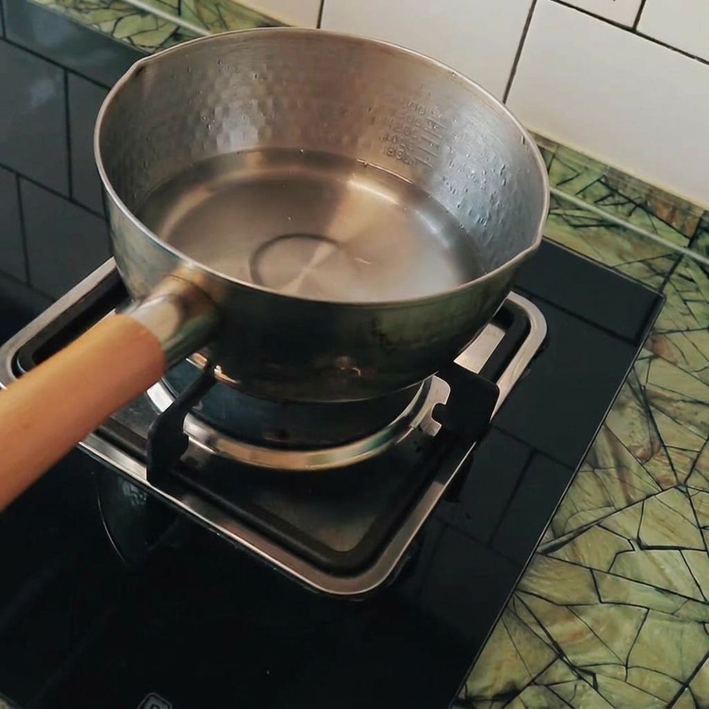 Kostki tofu wrzucane do wrzącej wody w garnku.