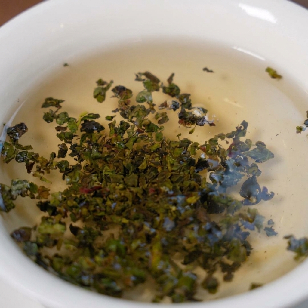 Zielone liście herbaty Tieguanyin rozwijające się w białej misce z gorącą wodą.