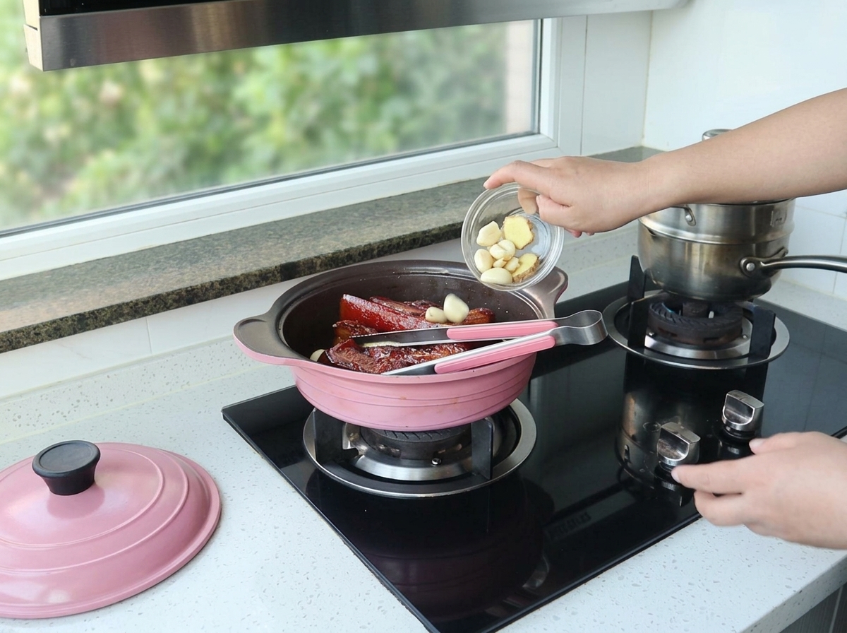 Ręka wrzuca ząbki czosnku do naczynia z duszącym się boczkiem.
