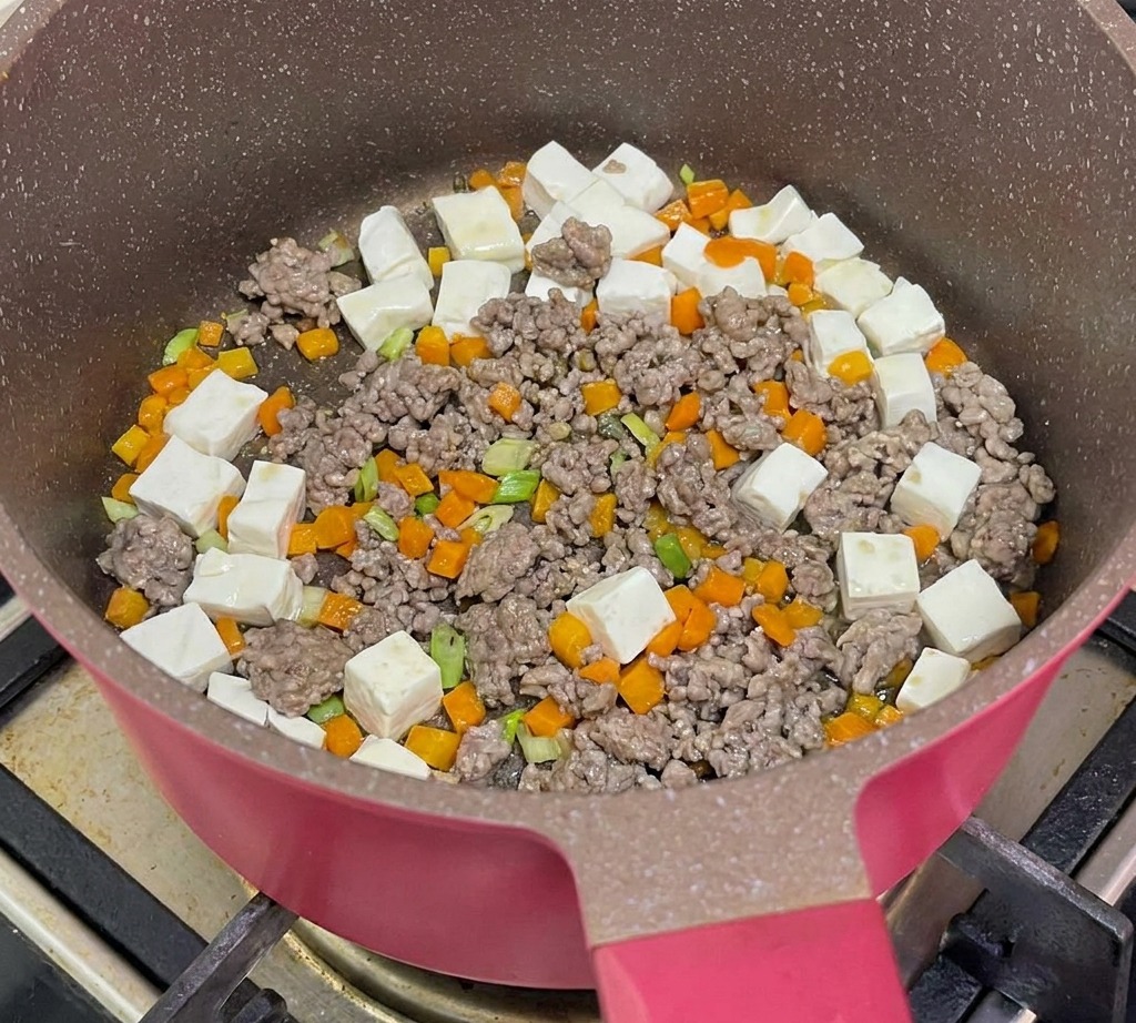 Wrzątek wlewany na patelnię z tofu, wołowiną i marchewką.