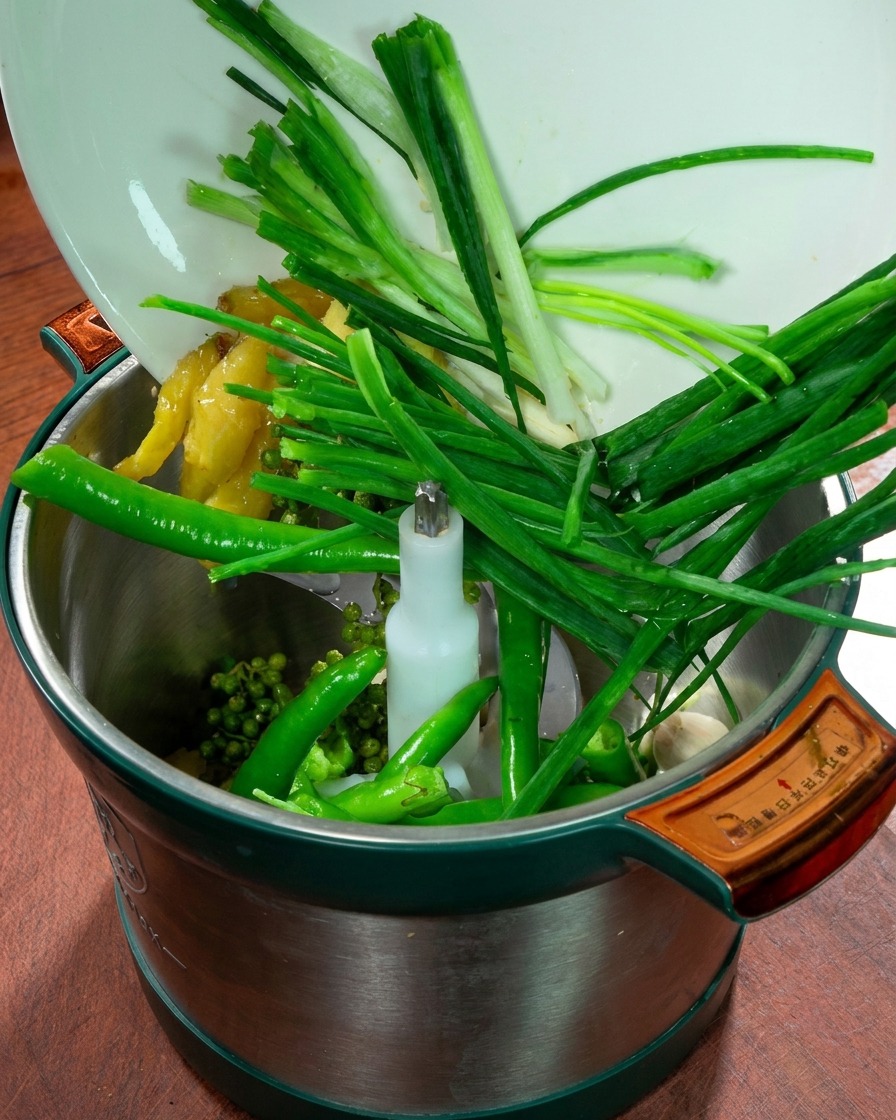 Pojemnik malaksera wypełniony zieloną cebulką, imbirem, czosnkiem, świeżymi zielonymi papryczkami chili i pieprzem syczuańskim.