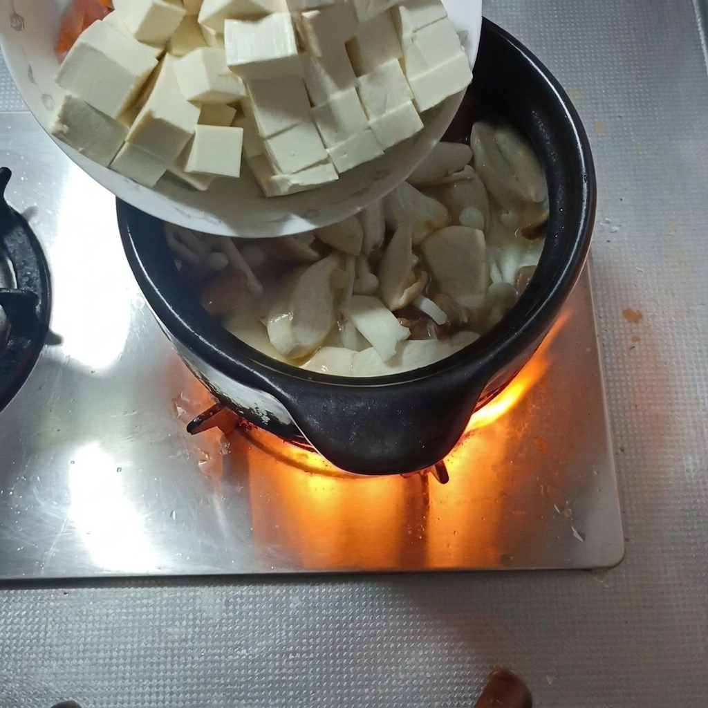 Kostki miękkiego tofu i plastry marchwi dodawane do zupy.