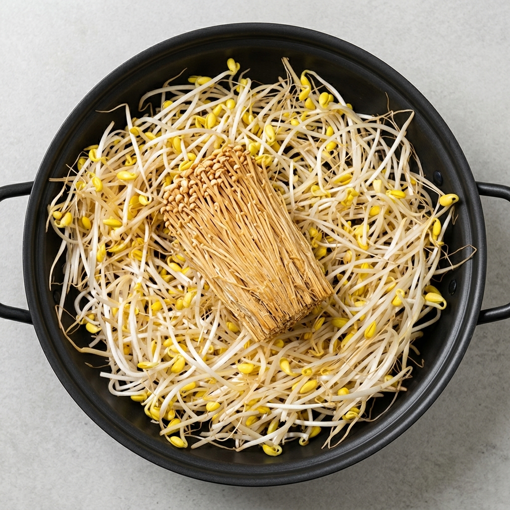 Różnorodne składniki, takie jak kiełki fasoli, tofu, grzyby enoki, spam i kiełbaski, starannie ułożone w garnku.
