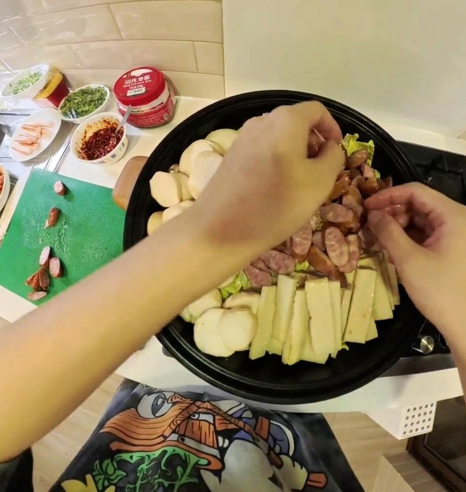 Różnorodne składniki gulaszu, w tym kimchi, mięso i warzywa, pięknie ułożone w płytkim garnku.
