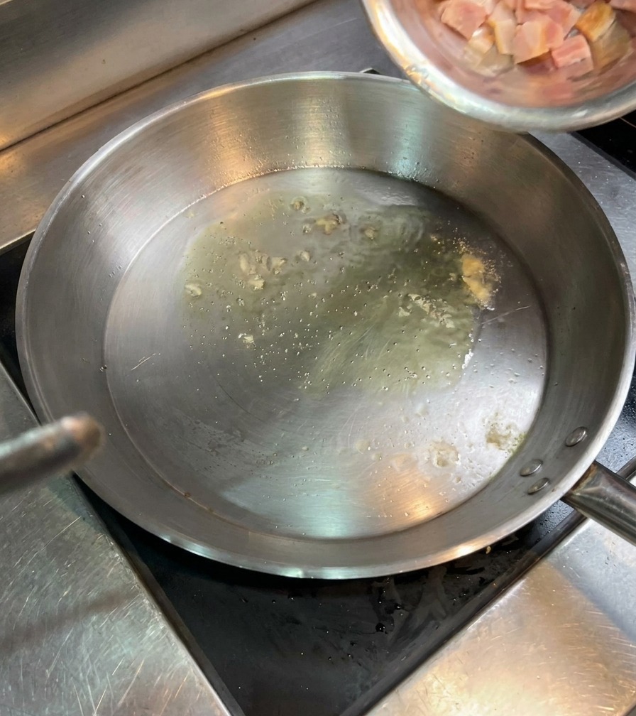 Kostki surowego boczku wsypywane z miski na patelnię z rozgrzanym olejem.