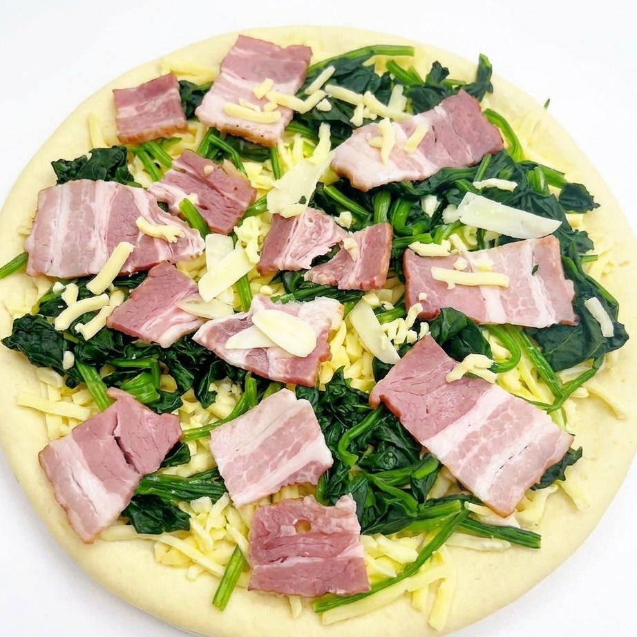 Widok z góry na gotową do pieczenia pizzę z dodatkami, posypaną lekką warstwą tartej mozzarelli.