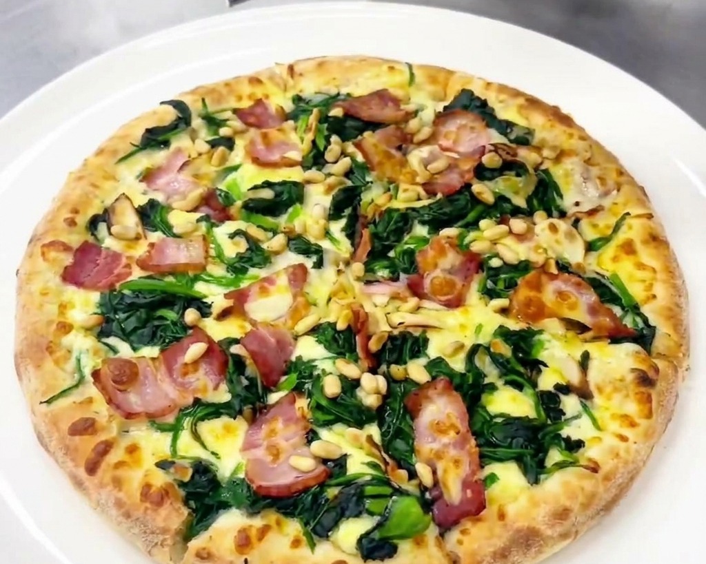 Osoba używająca tarki do dodawania świeżych płatków twardego sera na gotową pizzę.