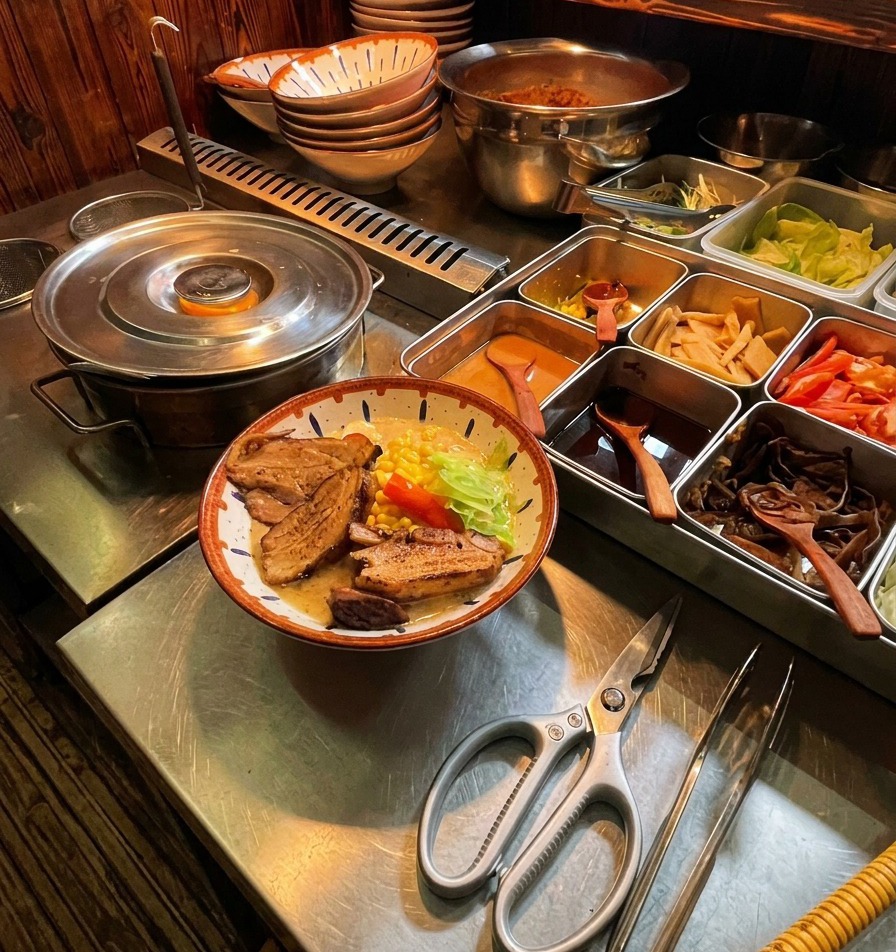Grube plastry zrumienionego boczku chashu wkładane do niemal gotowego ramenu za pomocą metalowych szczypiec.
