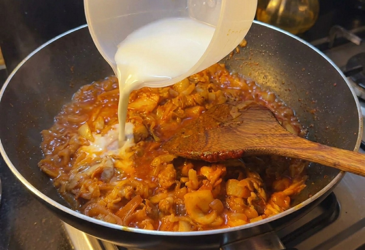 Wlewanie mlecznobiałej wody ze skrobią do patelni z gotującą się wołowiną i kimchi w gęstym sosie.