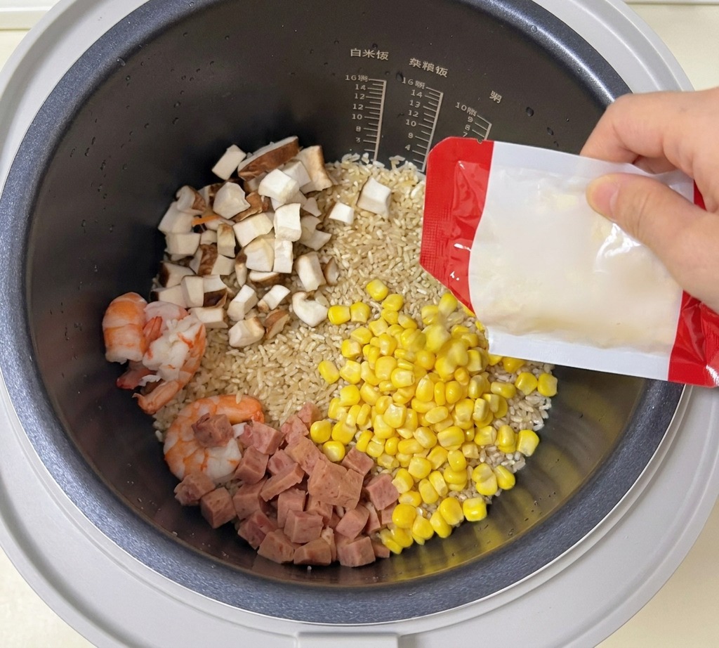 Ziarna kukurydzy wsypywane z opakowania do ryżowaru z krewetkami i grzybami.