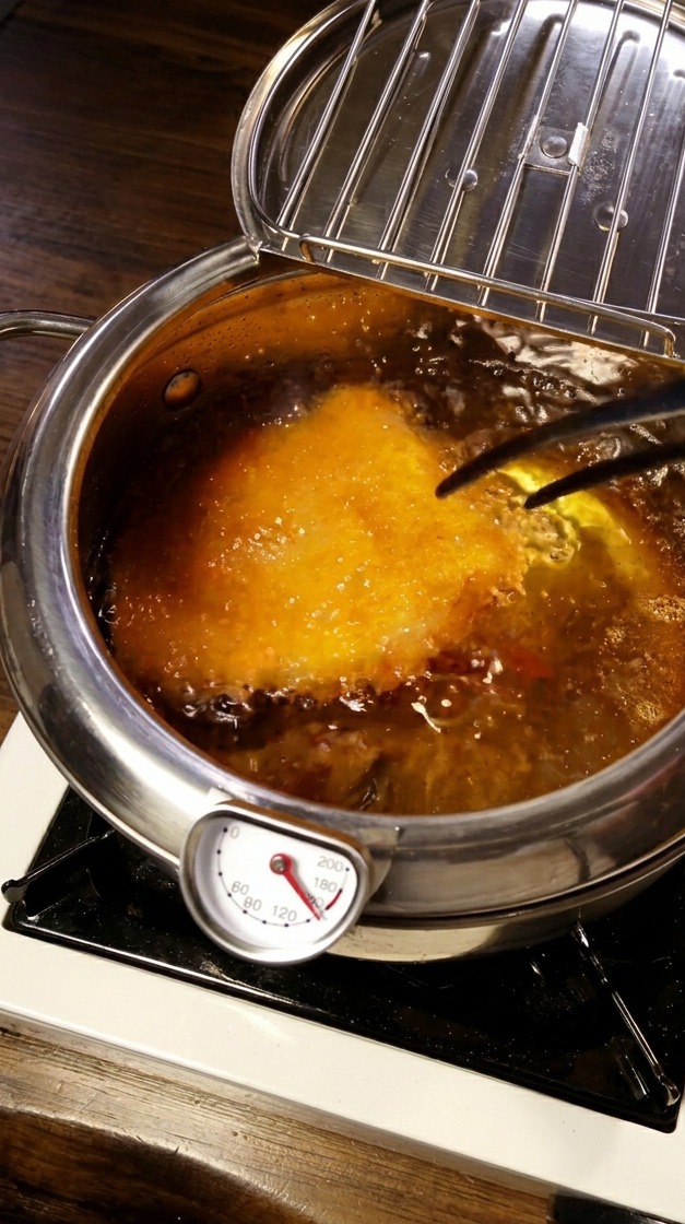 Panierowany kotlet smażący się w gorącym oleju z widocznym termometrem kuchennym