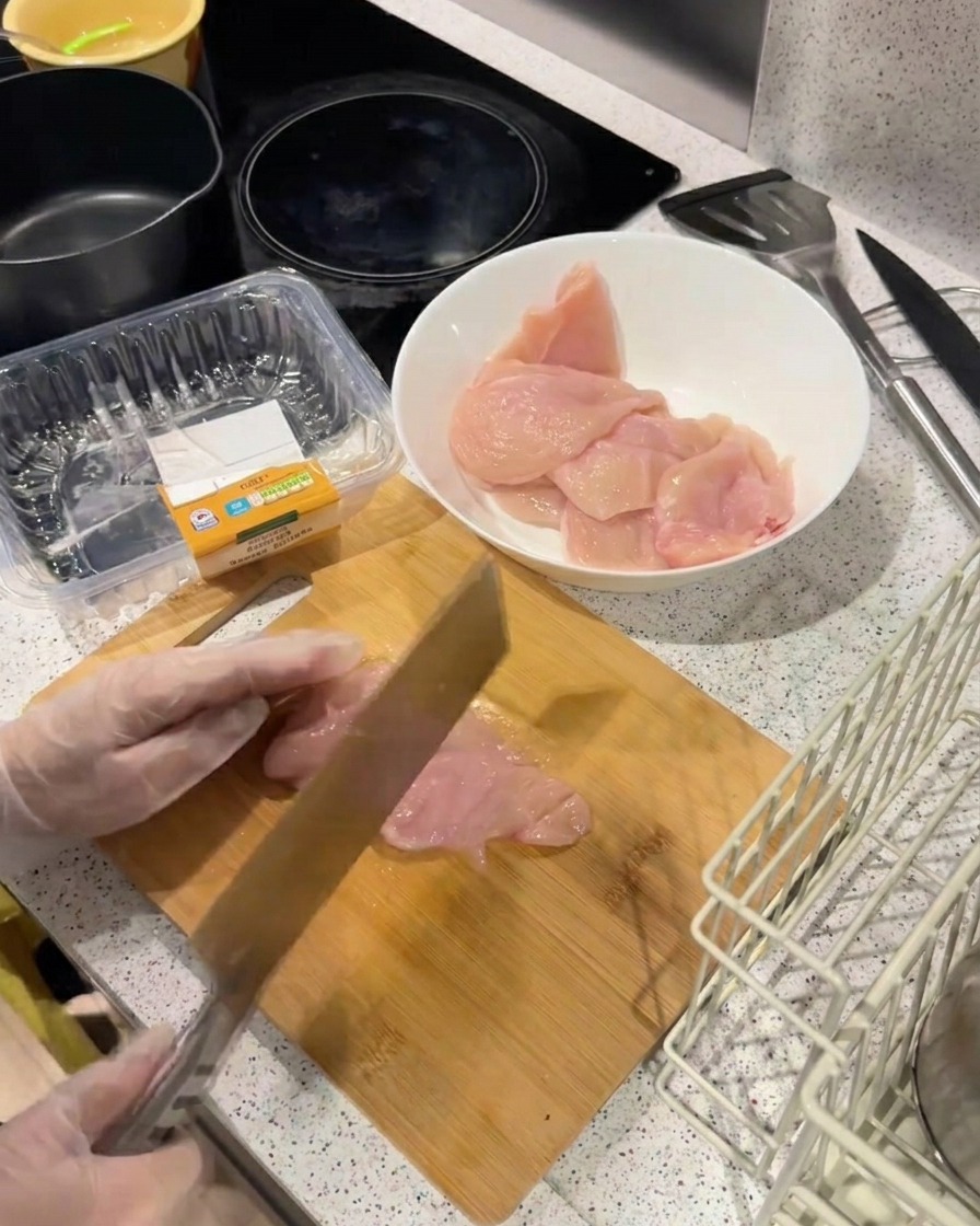 Tylna część ciężkiego noża uderzająca w cienki filet z kurczaka na drewnianej desce w celu jego rozbicia.