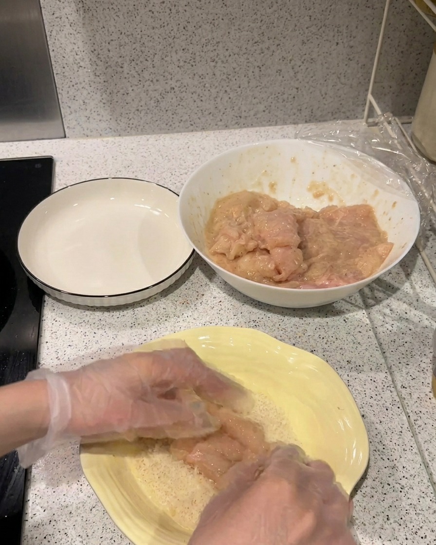 Marynowany filet z kurczaka dociskany do talerza z jasną bułką tartą Panko.
