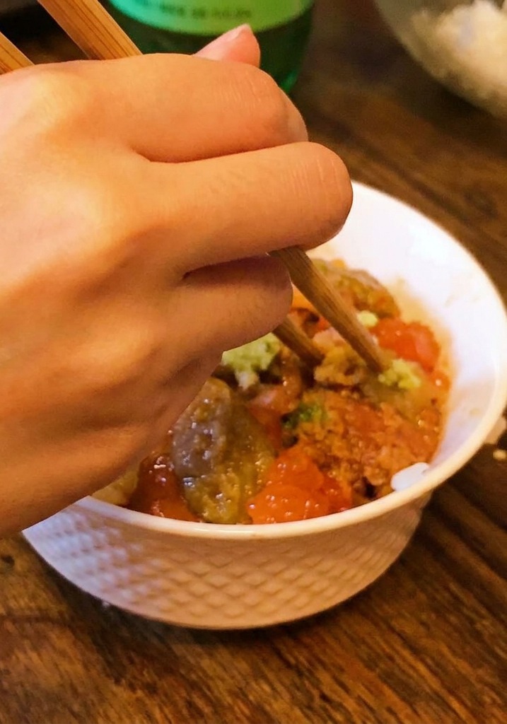 Dłoń używająca pałeczek do nałożenia niewielkiej ilości wasabi na środek miski z jeżowcem i kawiorem.