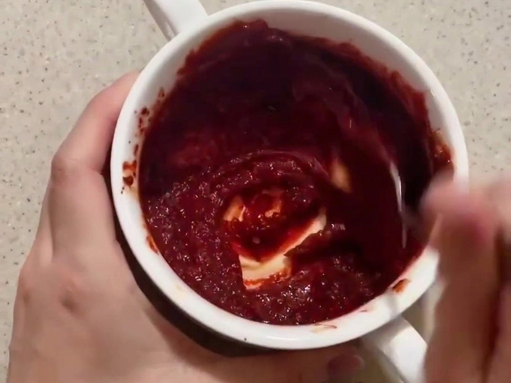Mieszanie gęstego, intensywnie czerwonego sosu na bazie gochujang w małej białej miseczce.