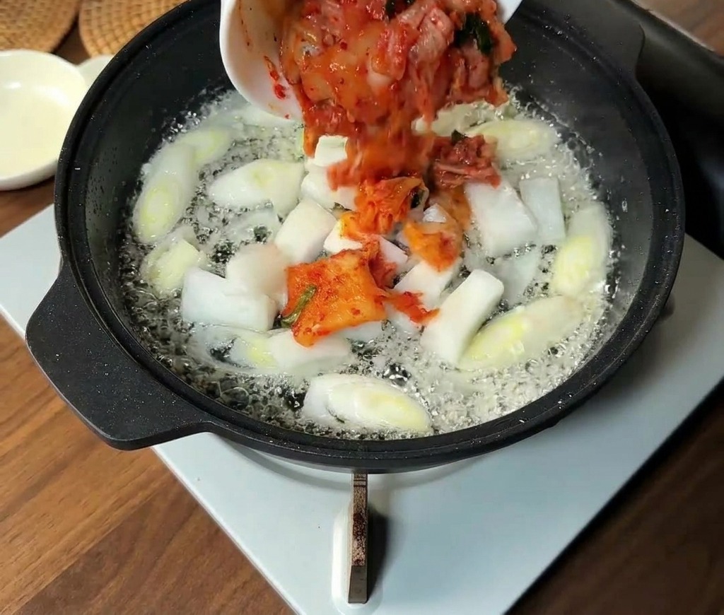 Posiekane kimchi i pióra cebuli dodawane na patelnię do podsmażonej dymki.