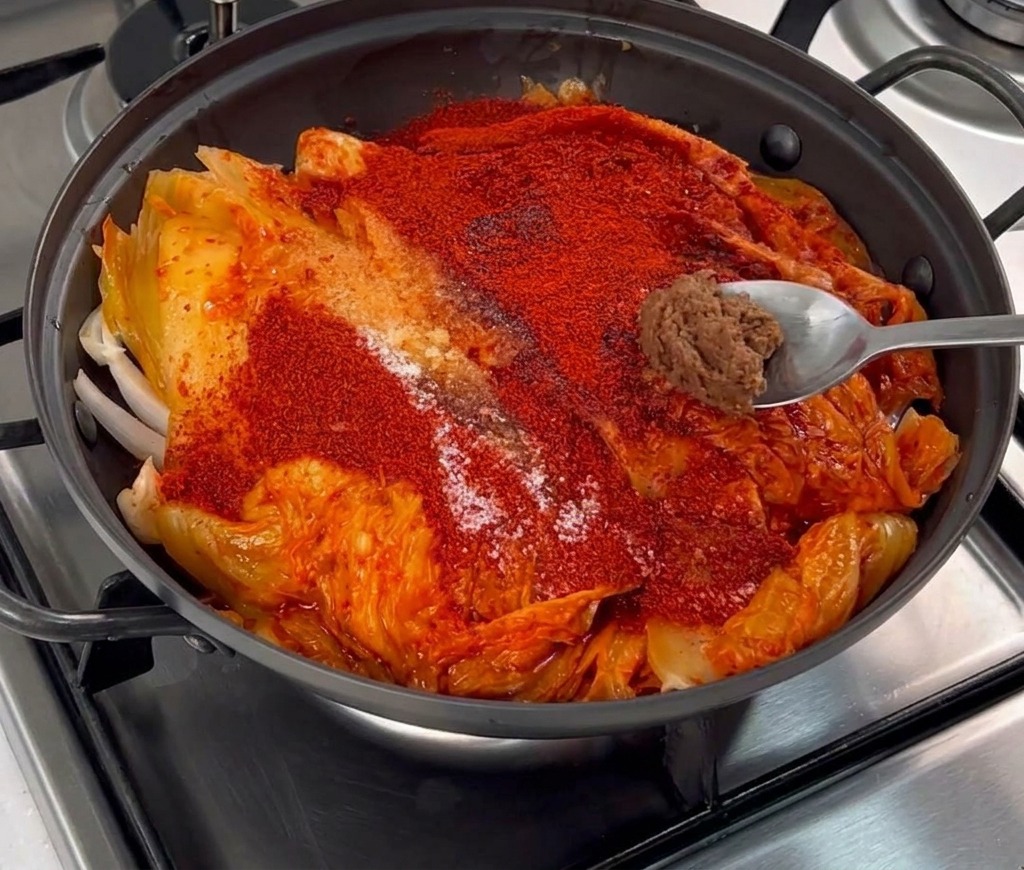 Porcja gęstej brązowej pasty sojowej na łyżce kładziona na warstwę chili i kimchi.
