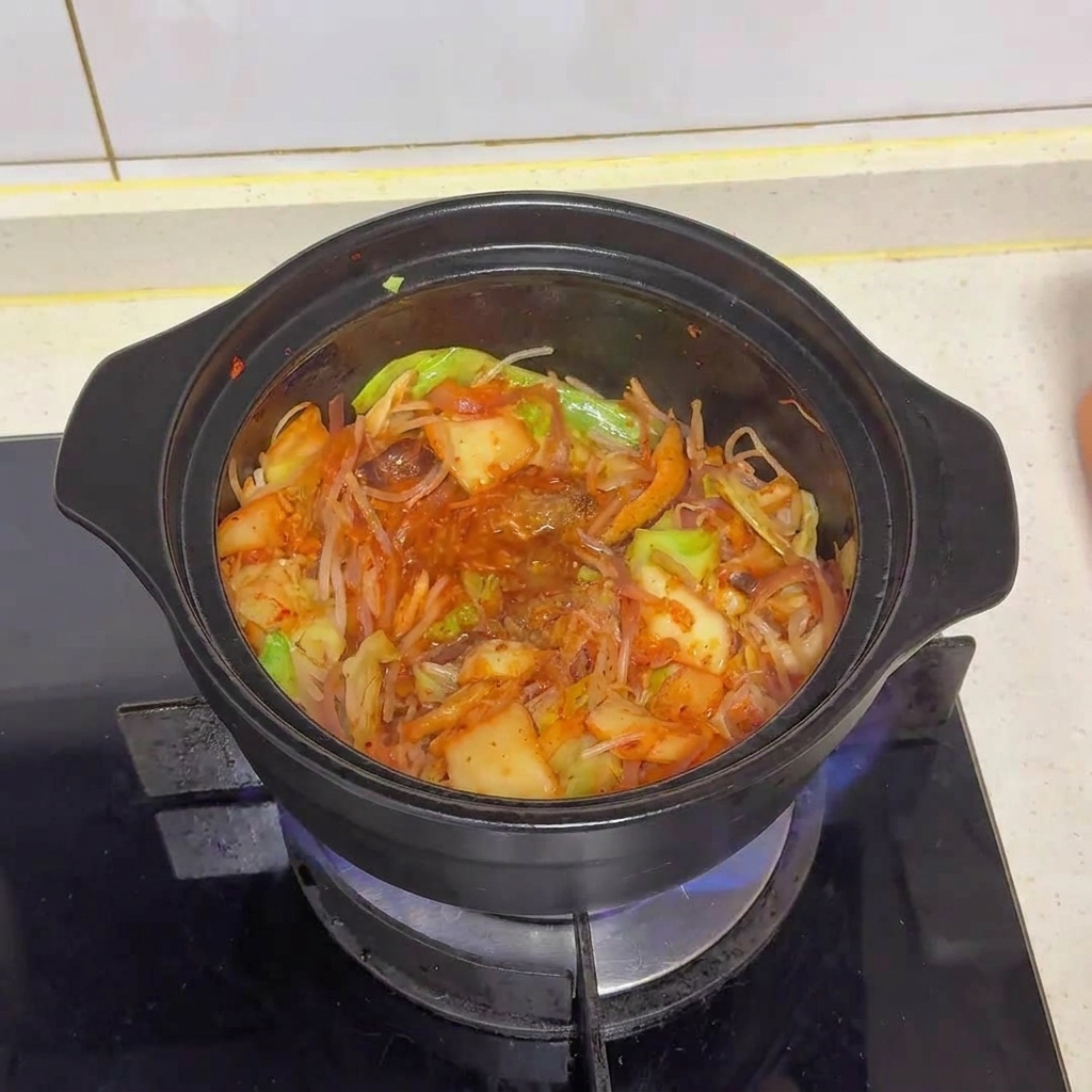 Mieszanka warzyw i kimchi w garnku po dodaniu przypraw, widoczne łączące się smaki.