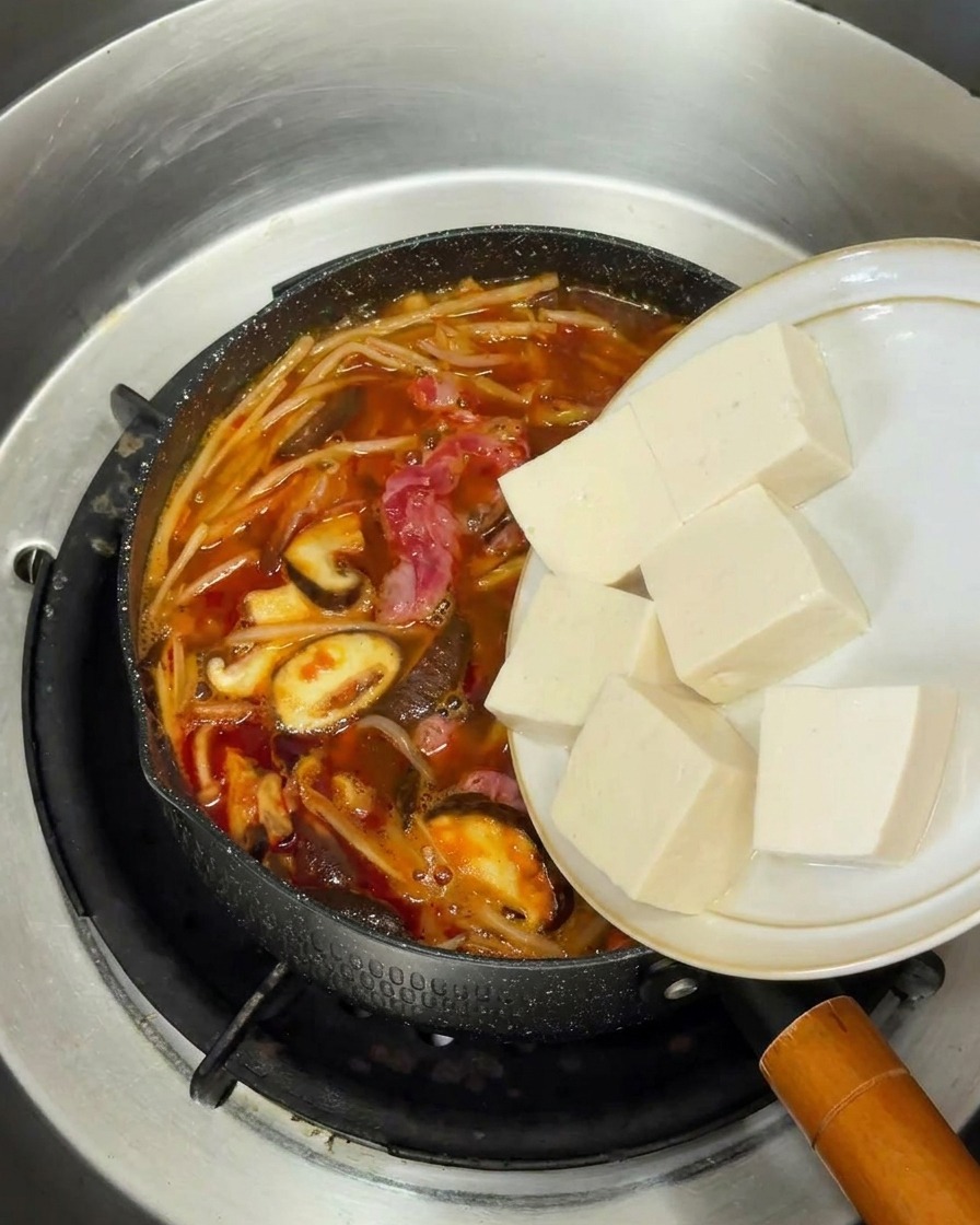 Kostki białego, miękkiego tofu dodawane do bulgoczącej koreańskiej zupy wołowej.