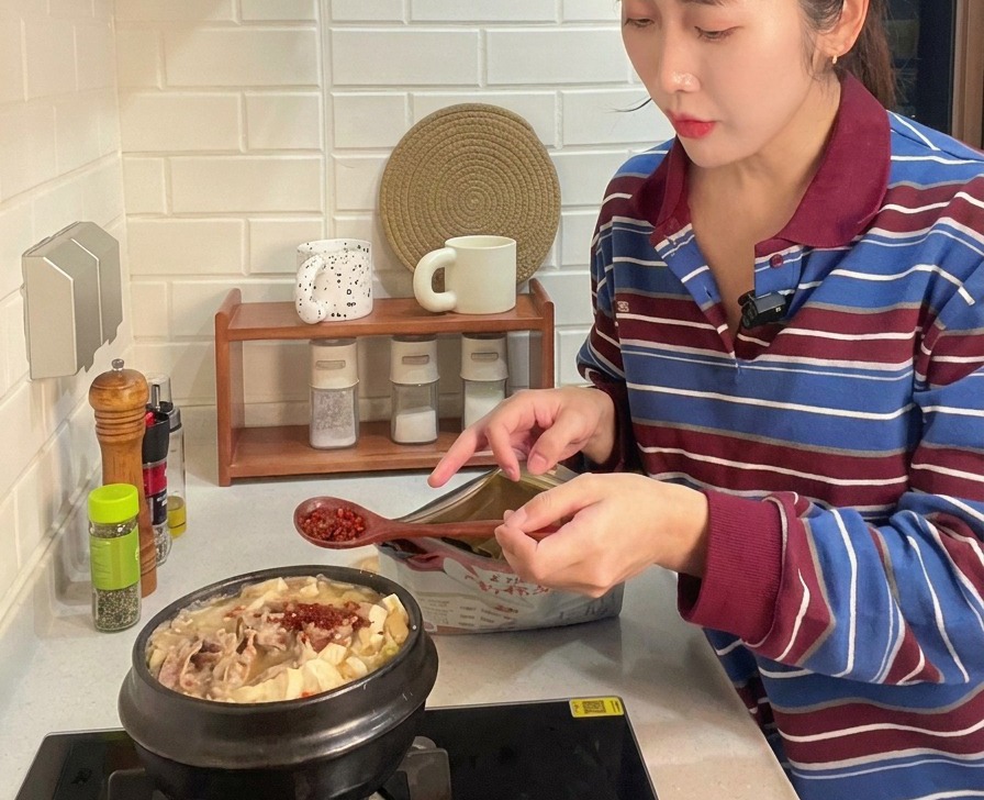 Drewniana łyżka dodająca jaskrawoczerwone płatki chili do bulgoczącego kociołka z wołowiną i tofu