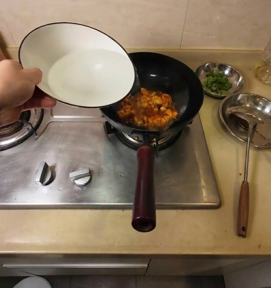 Gorąca woda wlewana z ceramicznej miski do woka z przyprawionym tofu.