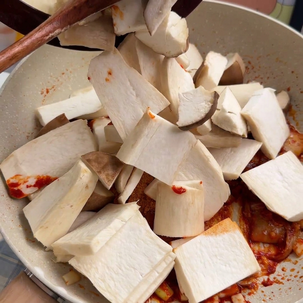 Grube plastry boczniaków mikołajkowych wrzucane na patelnię i mieszane z czerwoną bazą chili.