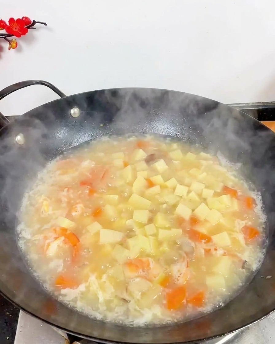 Widok z góry na wok pełen zupy z tofu, krewetkami i małymi brązowymi grzybami.