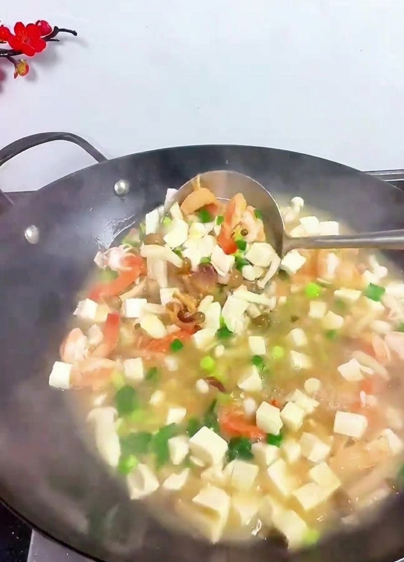 Chochla unosząca tofu, krewetki i zioła w parującym woku.