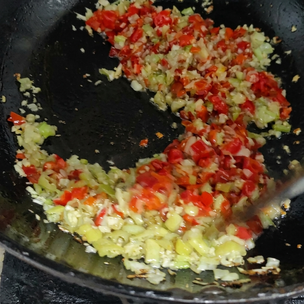 Kolorowa mieszanka posiekanego czerwonego i zielonego chili smażona z aromatami na patelni.