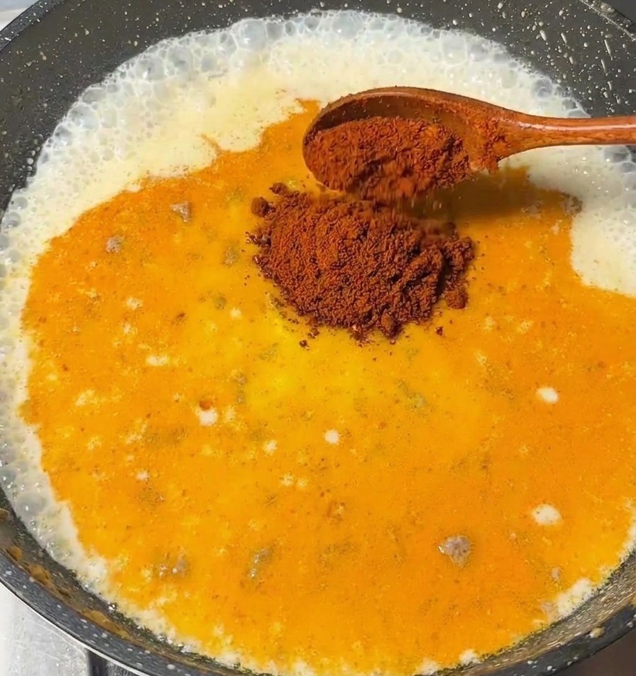 Drewniana łyżka dodająca kawałki japońskiej kostki curry do bulgoczącego sosu mlecznego.