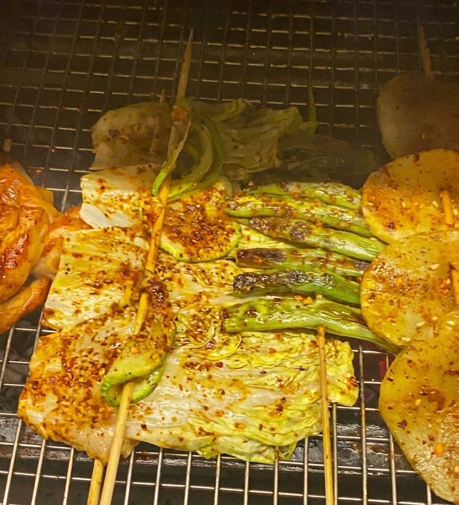 Zbliżenie na grillowanego kurczaka, kapustę i cukinię smarowane czerwonym sosem BBQ i posypane dymką.