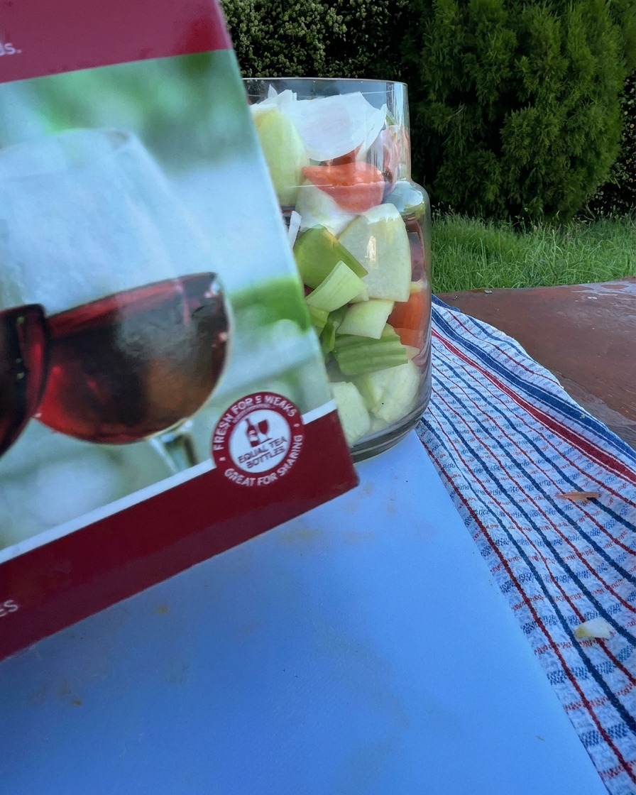 Czerwone wino wlewane do szklanego naczynia z surowymi żebrami i warzywami.